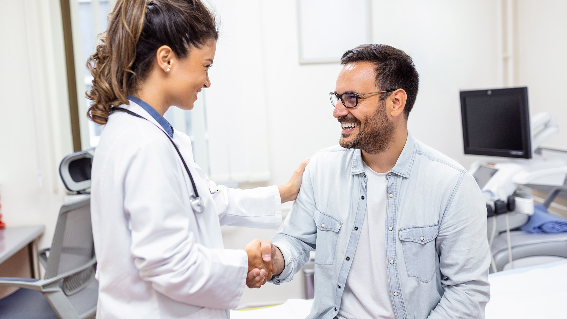 Patient shaking doctor's hand while doctor reassures him.